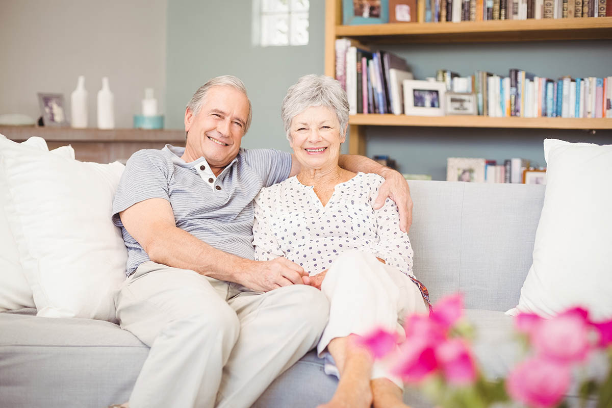 Sage Oak of Lake Charles | Portrait of smiling senior couple sitting on sofa in living room