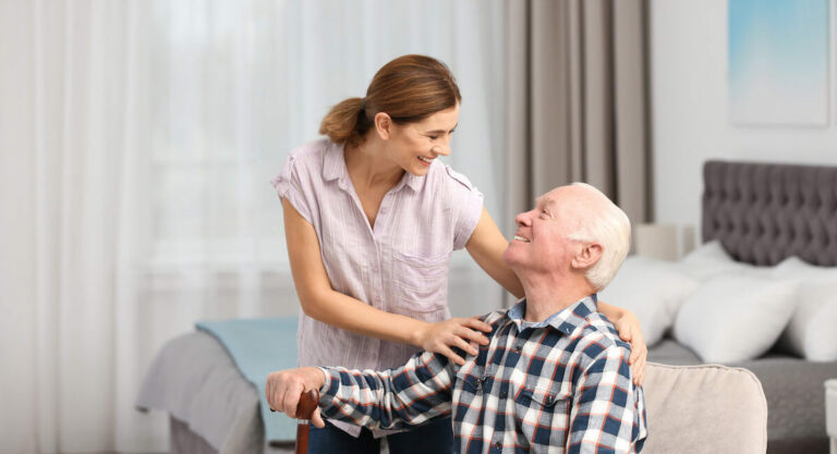 Sage Oak of Lake Charles | Senior man with a cane sitting down and smiling at his caregiver