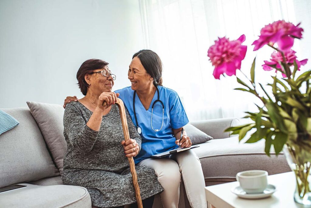 Sage Oak of Lake Charles | Happy senior woman and her caregiver talking while sitting on the couch