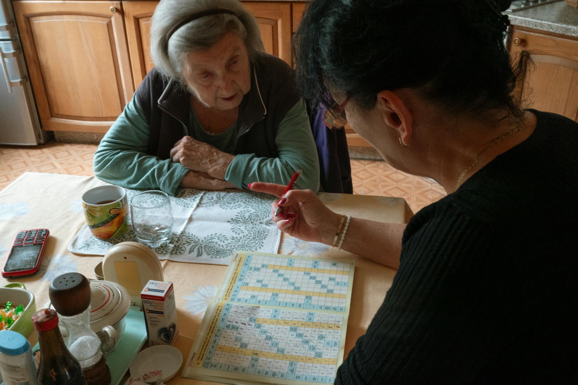 senior woman solving crossword with caregiver